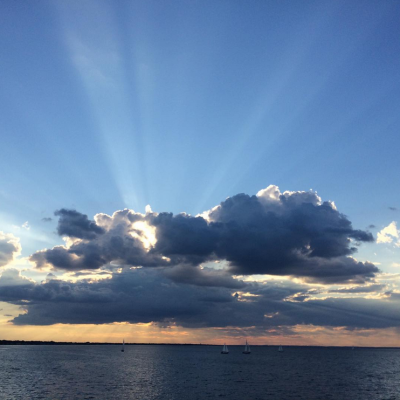 The sun's rays illuminating the clouds over the ocean.
