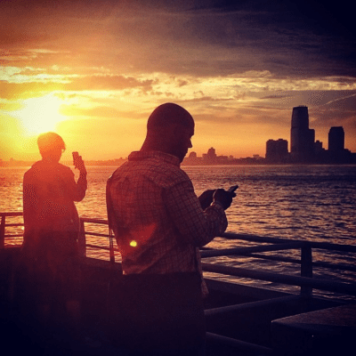The sun sets over New York city while passengers look out over the water