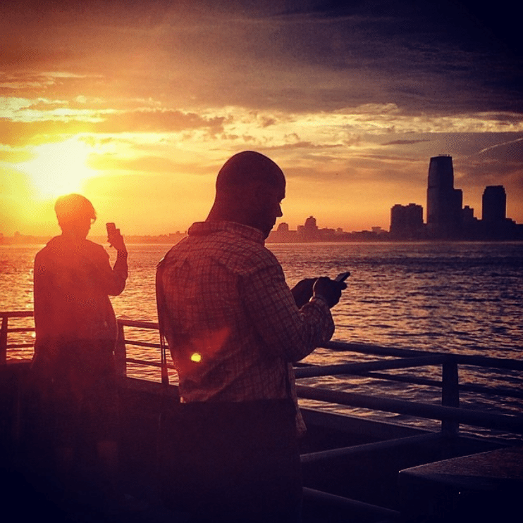 The sun sets over New York city while passengers look out over the water