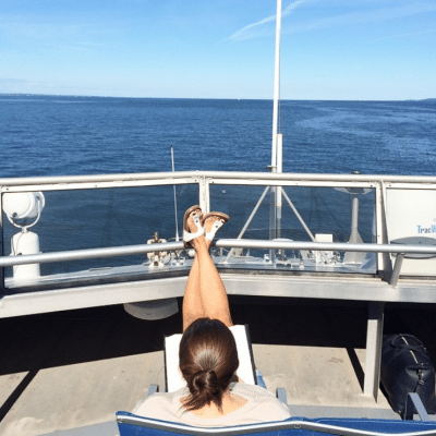 Women with legs up on the railing looking out on the water