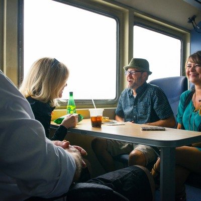 Friends enjoy the ride as they eat snacks around a table on the ferry