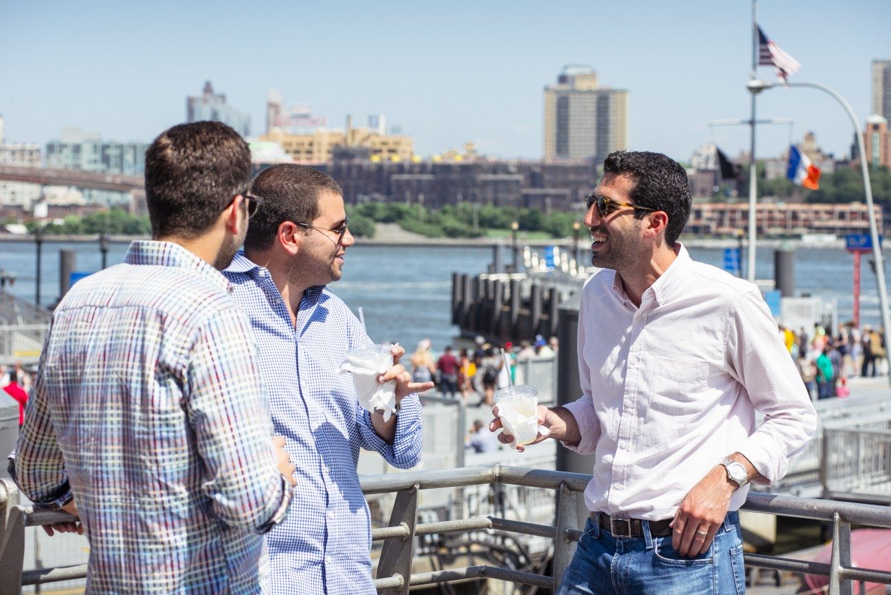 Several young professionals enjoy beverages on the deck of the ferry as it leaves port