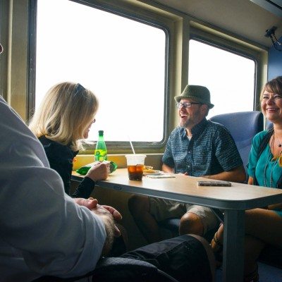 Friends enjoy the ride as they eat snacks around a table on the ferry