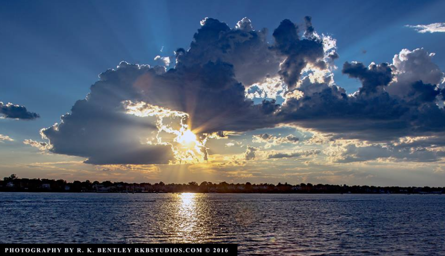 The sun's rays illuminating the clouds over the ocean.