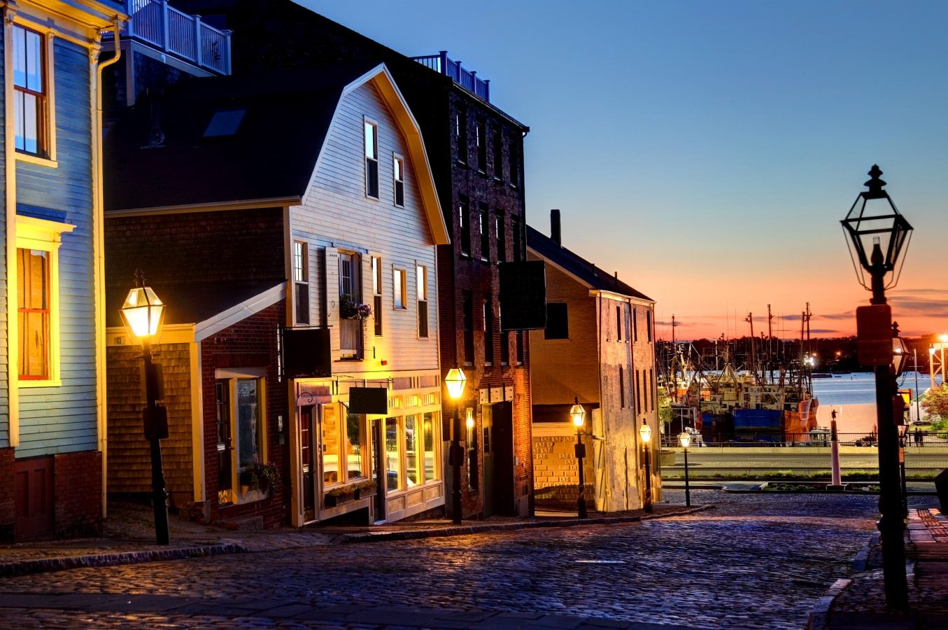 A row of houses and shops on a historic road leading to the water in New Bedford as the sun sets