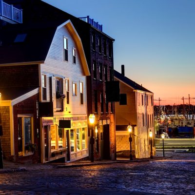 A row of houses and shops on a historic road leading to the water in New Bedford as the sun sets