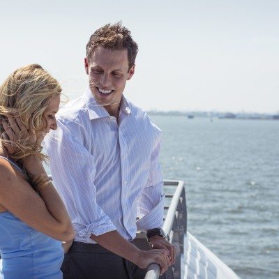 Couple looks out over the water from the deck of the ferry on a sunny day.