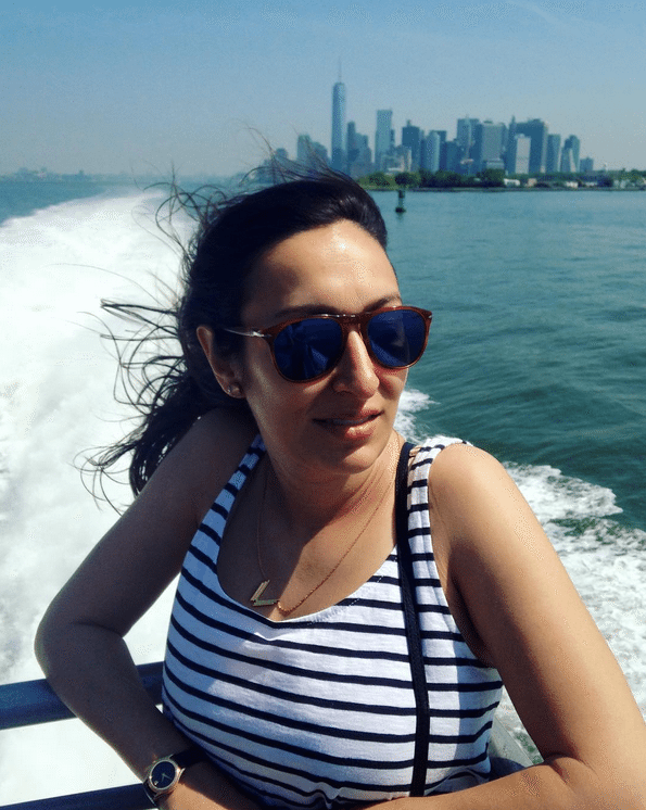A woman wearing sunglasses on the ferry with Manhattan in the background