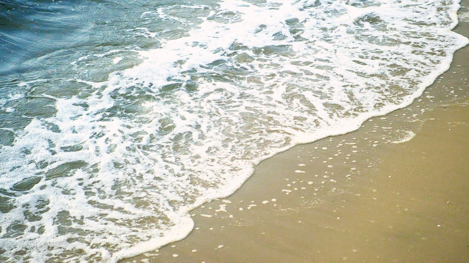 Waves peacfully crashing onto Sandy Hook beach's shore